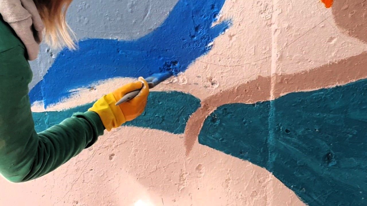 Woman holding a paintbrush painting a wall.