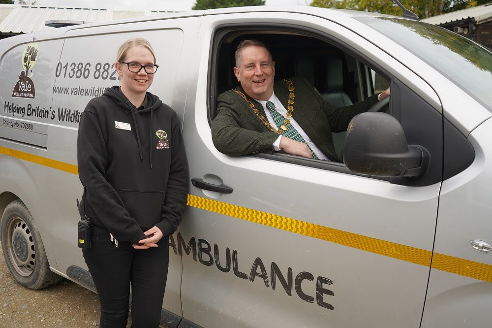A woman stood in front of a van with a man leaning out of the window