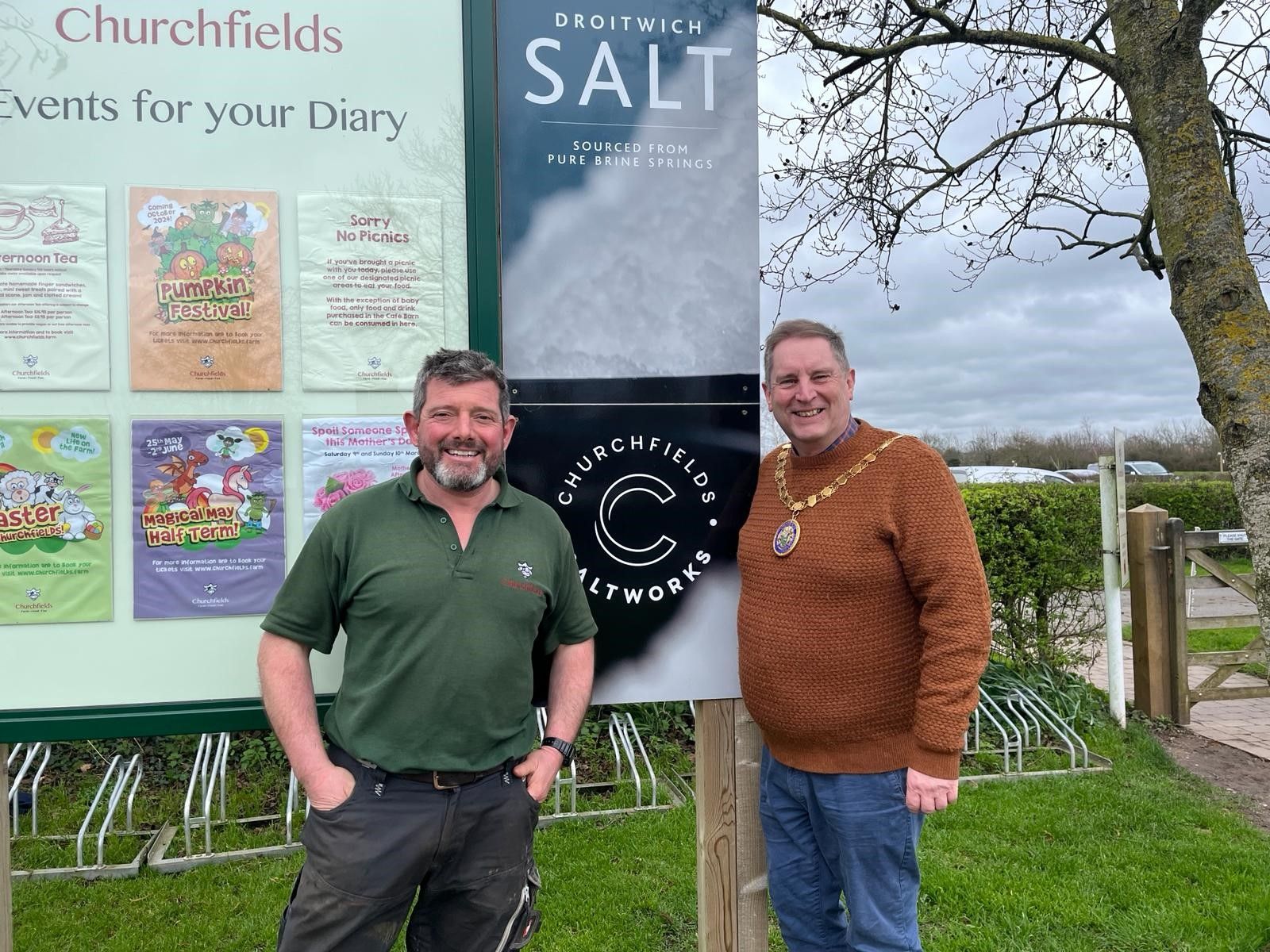 Two men stood in front of a sign.