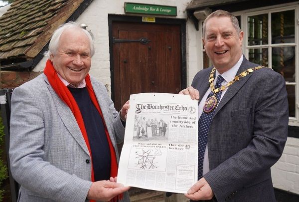 Two man holding either side of a newspaper.