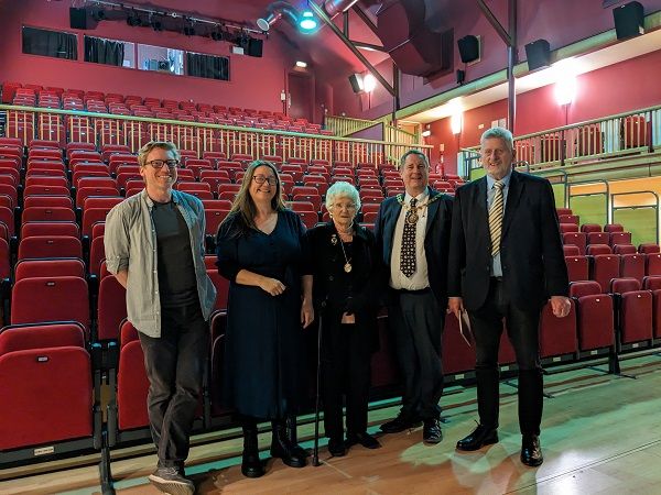 Group of people stood in front of some theatre chairs.