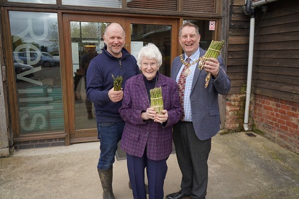 Three people holding asparagus.