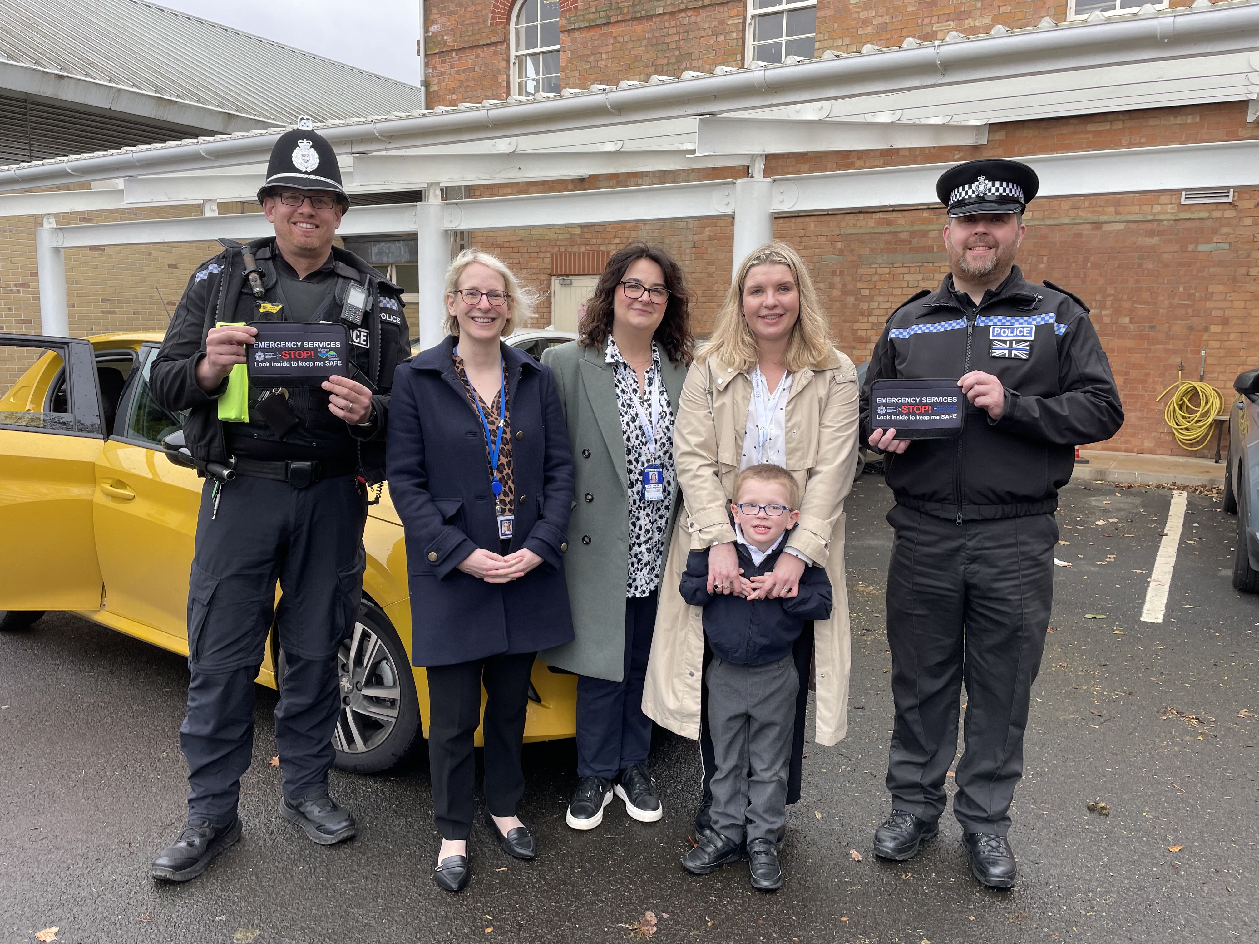 A group of people stood in front of a car.