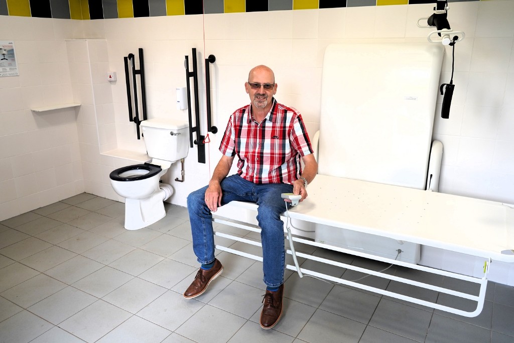 A man sat on a bench in a Changing Places toilet