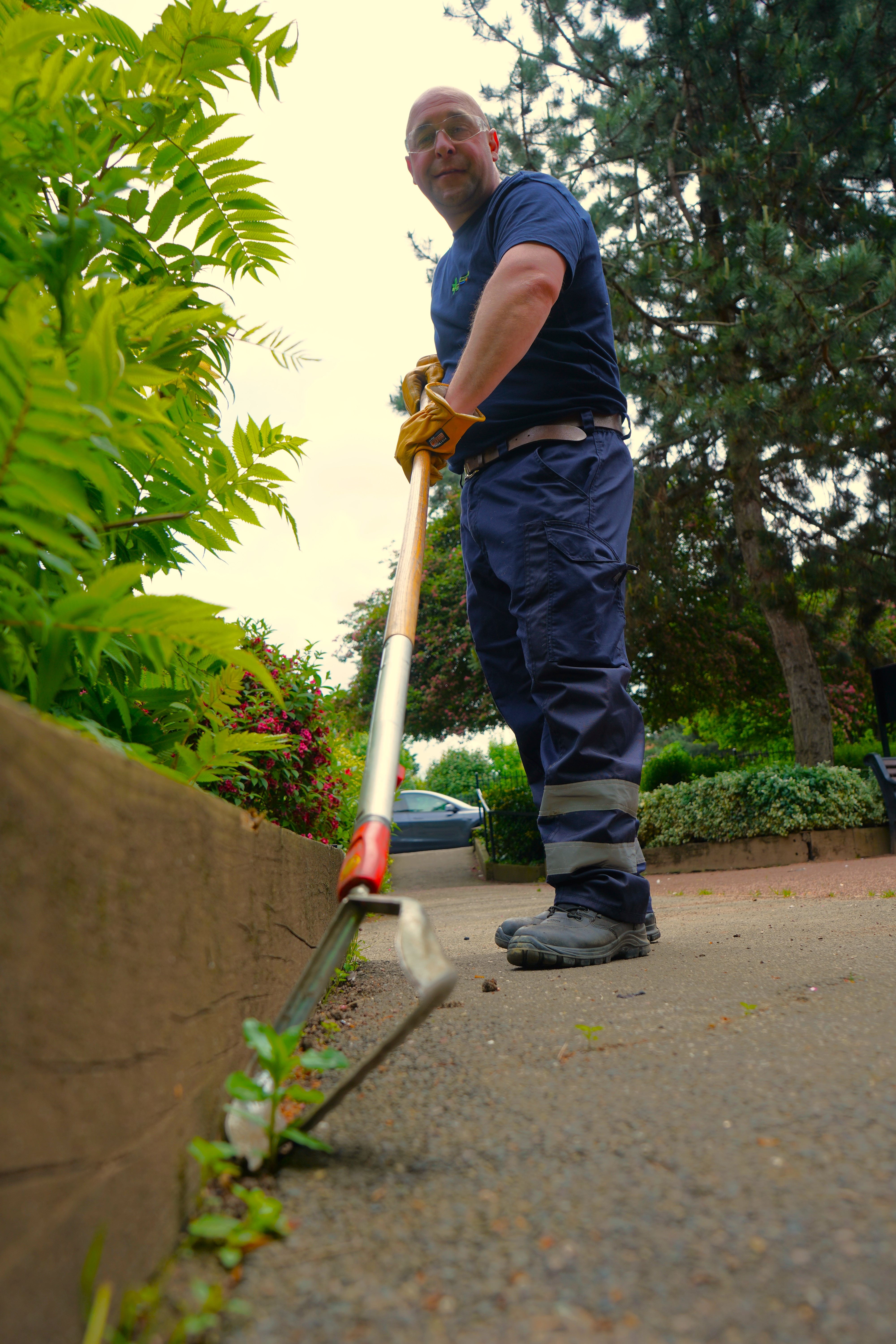 A man using a hoe to remove a weed
