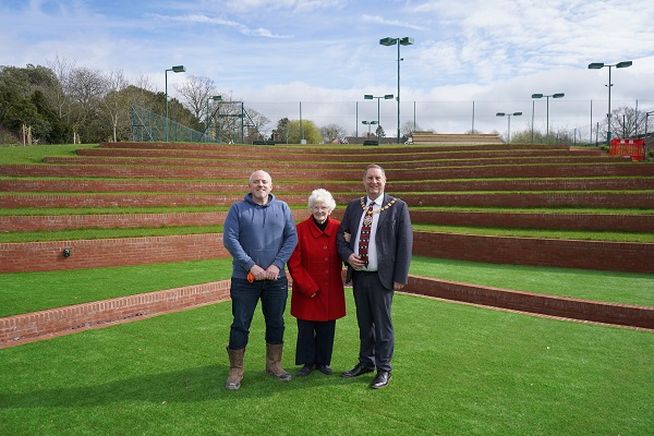 Three people stood in front of an outdoor amphitheatre.
