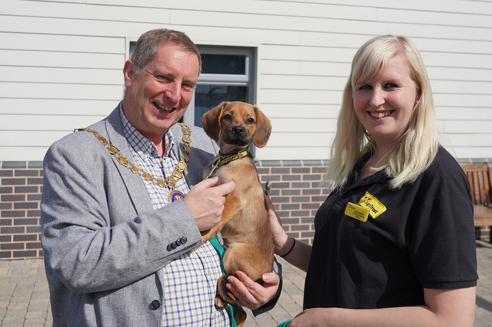 A man holding a dog with a woman standing next to him.