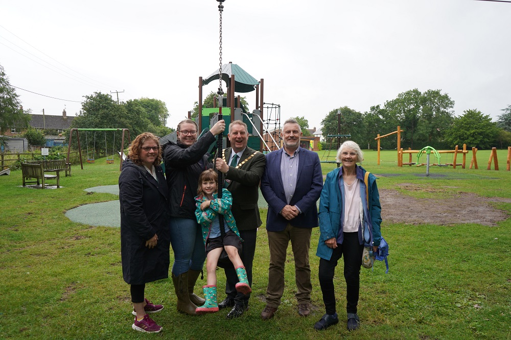 A group of people standing in front of a park around a zip wire