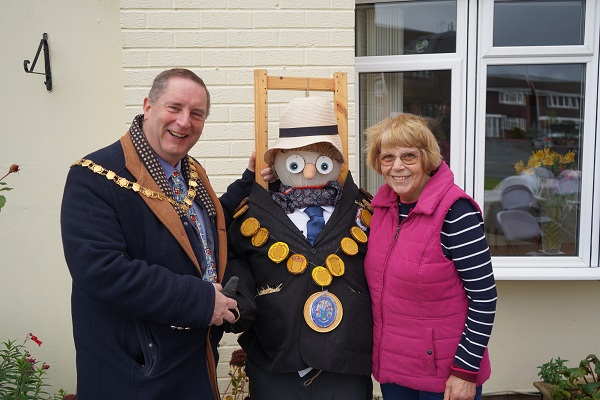 A man and woman stood either side of a scarecrow.