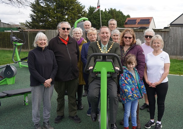 A group of people stood around an outdoor exercise bike.