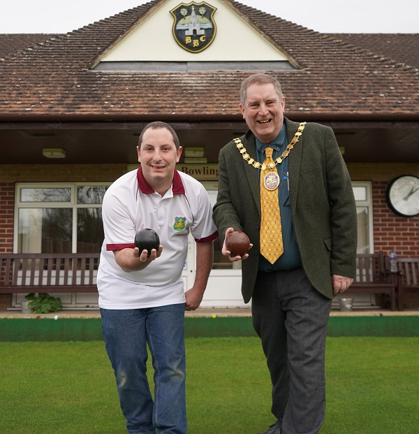 Two men holding bowls balls.
