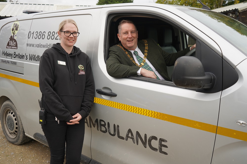 A woman stood in front of a van with a man leaning out of the window