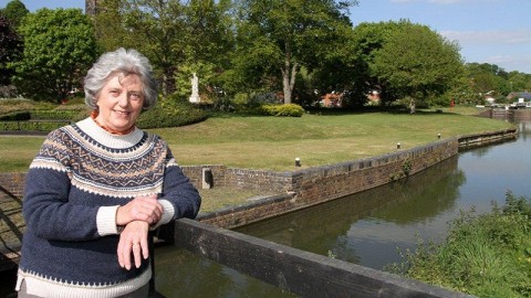 Woman leaning on a fence over a canal