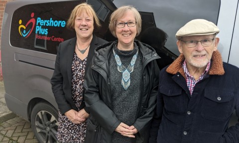 Three people stood looking happy in front of a van